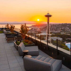 Glass railing on Spire Seattle's rooftop patio with a view of the Space Needle during the Golden Hour